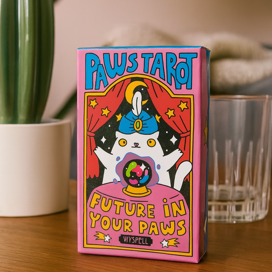 Paws Tarot card box with a cat and crystal ball illustration on a wooden surface.
